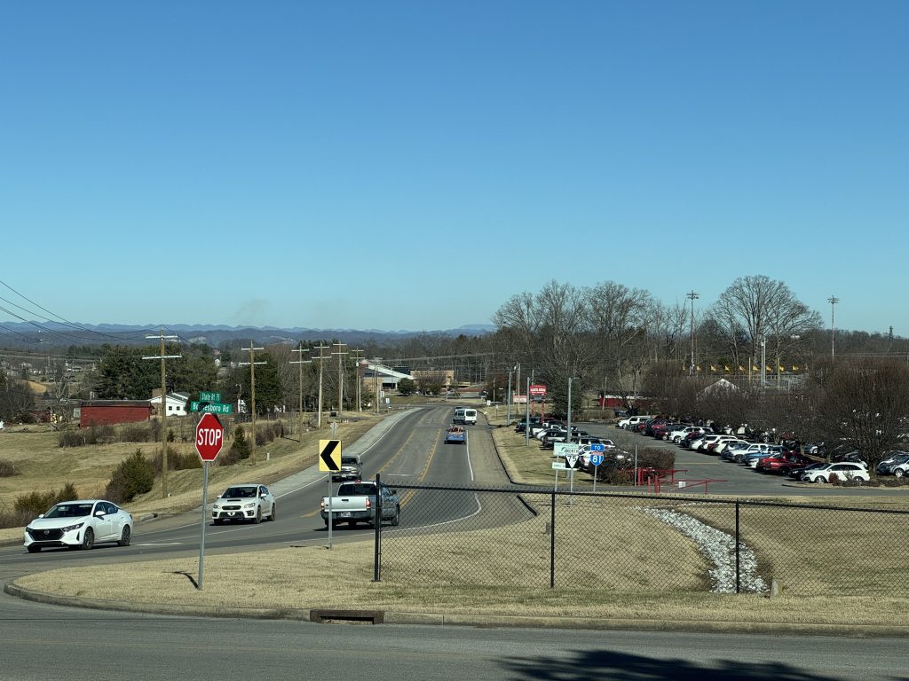 Picture looking northeast down State Route 75, a two-lane road with a center turn lane. Daniel Boone High School's parking lot is on the right.