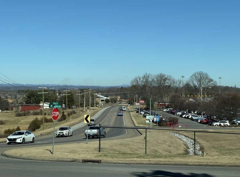 Picture looking northeast down State Route 75, a two-lane road with a center turn lane. Daniel Boone High School's parking lot is on the right.