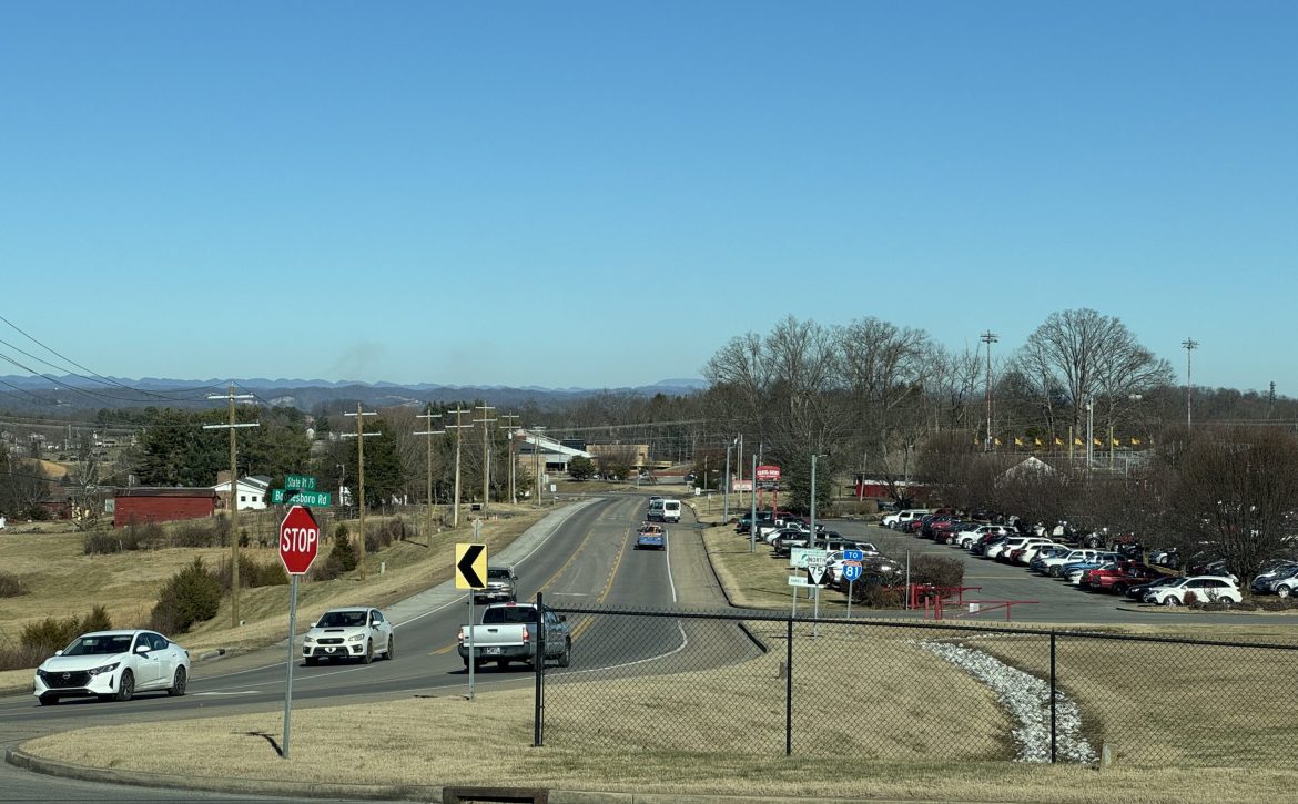 Picture looking northeast down State Route 75, a two-lane road with a center turn lane. Daniel Boone High School's parking lot is on the right.